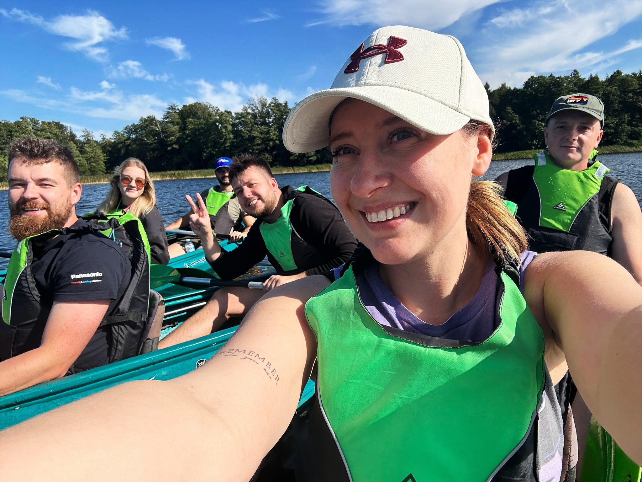 Group of six people kayaking on a sunny day, wearing green life vests.