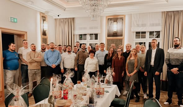 Group of people standing in a decorated room with a table of gifts.