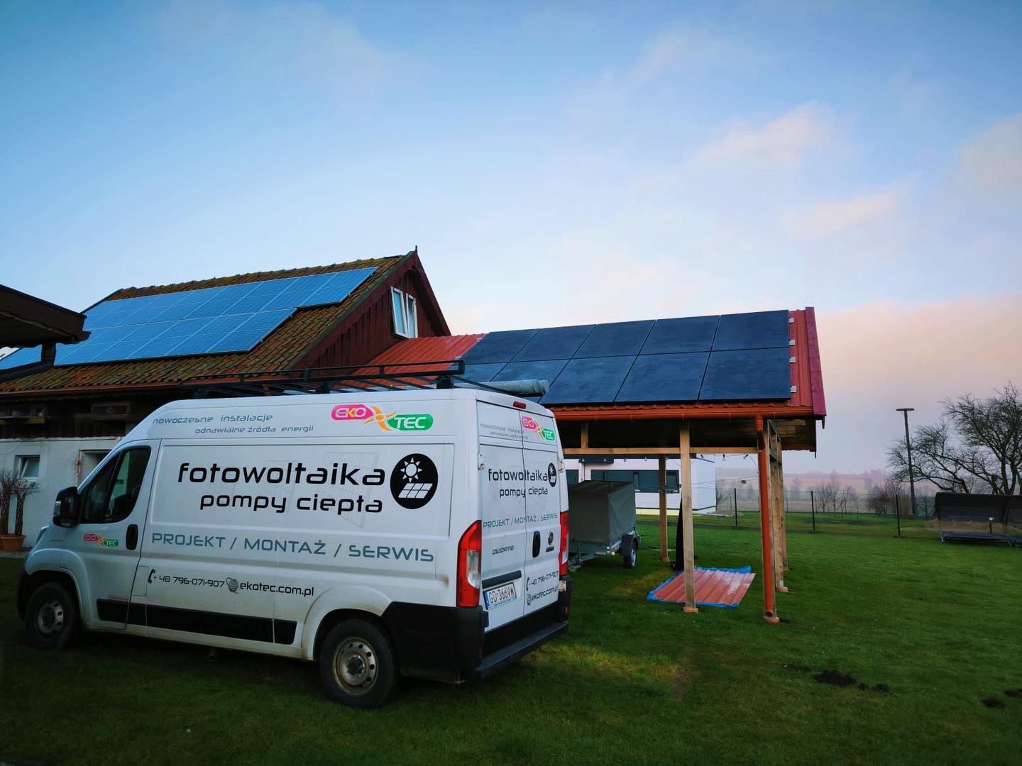 White van parked beside house with solar panels on roof at sunrise.