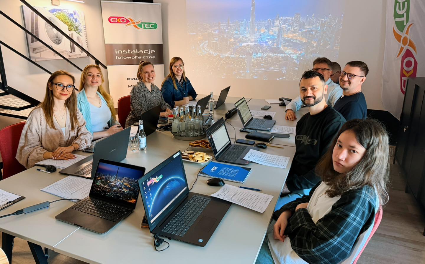 Group of people at a conference table with laptops and documents.