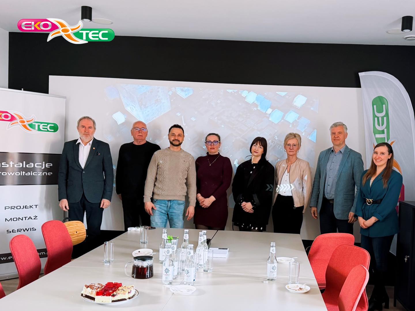 Eight people standing in a conference room with Eko-Tec banners.