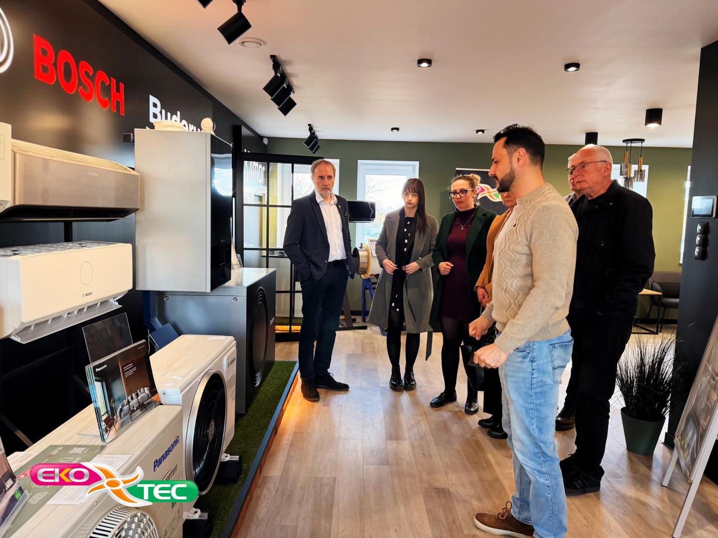Group of people discussing in a showroom with Bosch appliances displayed.